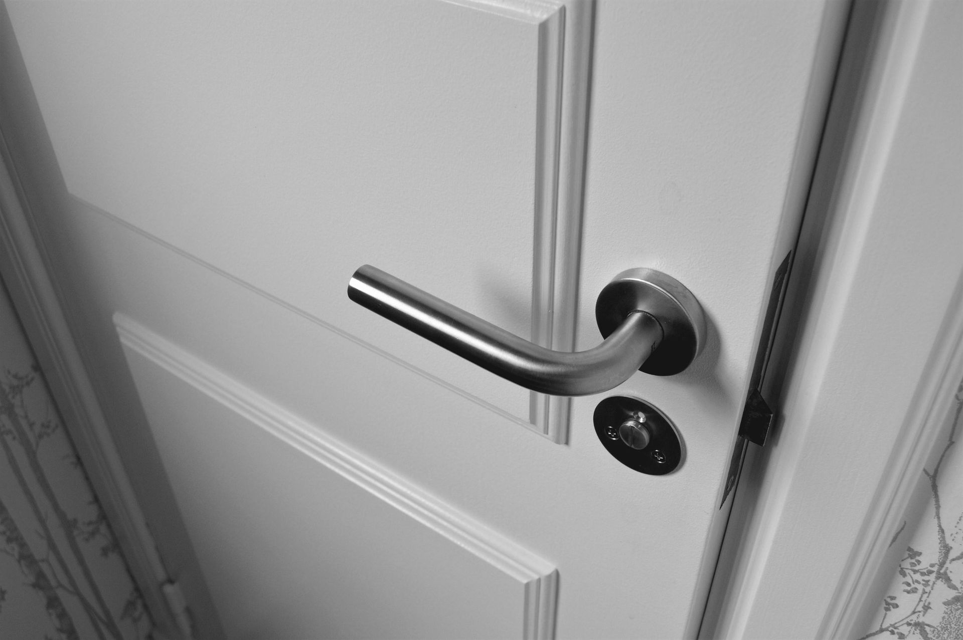 A close up of a door handle on a white door.